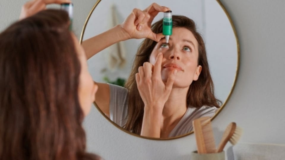 Vrouw die oogdruppels in doet